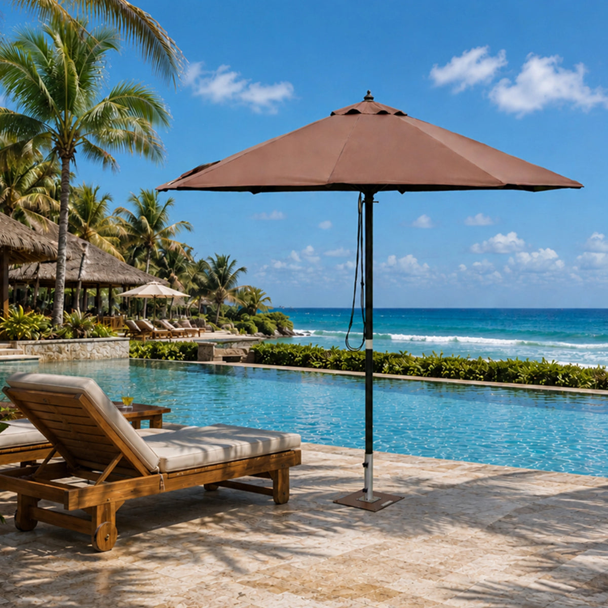 A large brown patio umbrella stands beside a resort pool with lounge chairs, palm trees, and the ocean in the background.