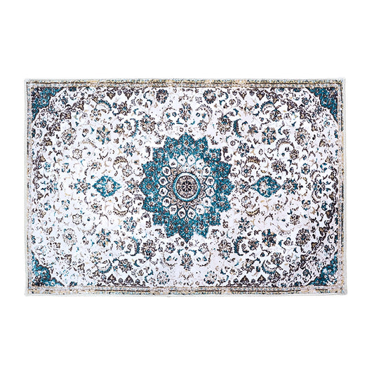 A rectangular area rug with a distressed traditional Persian design, featuring a central blue and white medallion and intricate floral patterns in blue, gray, and white.